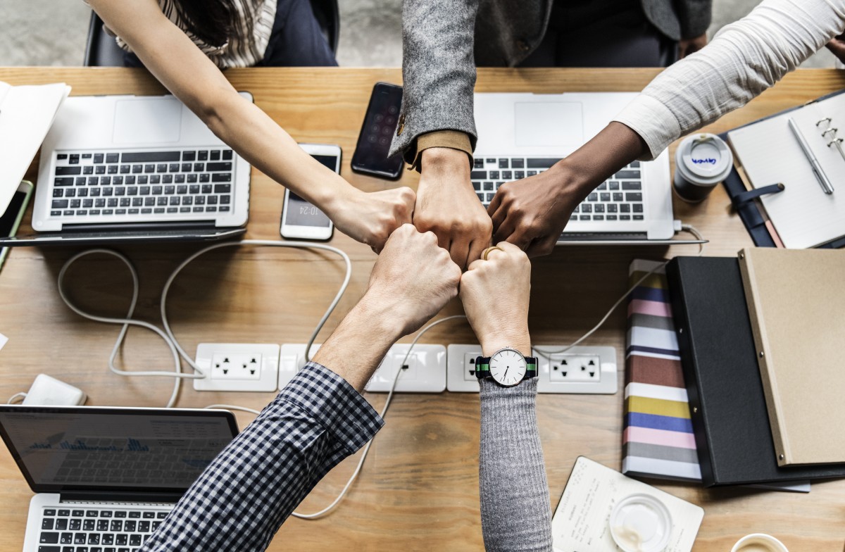 A stock photo showing people bumping fists together in a shared office